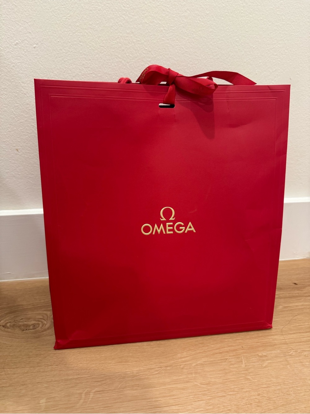 Omega Red Gift Bag with Gold Emblem and Ribbon
